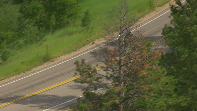 美国南达科塔州斯特吉斯森林环绕的170号高速公路上骑车的人的照片视频素材