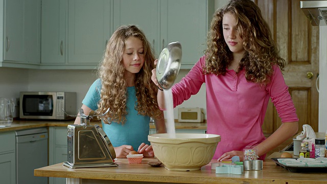 英国汉普斯特德伦敦，女孩们在厨房里准备烘焙，将原料倒入搅拌碗中视频下载