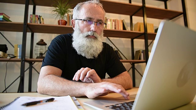长着大胡子的成年男子在用笔记本电脑工作视频素材