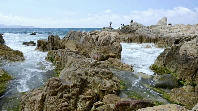 MS拍摄的海浪冲击花岗岩在海滩和捕鱼的人/普罗诺，科西嘉，法国视频下载