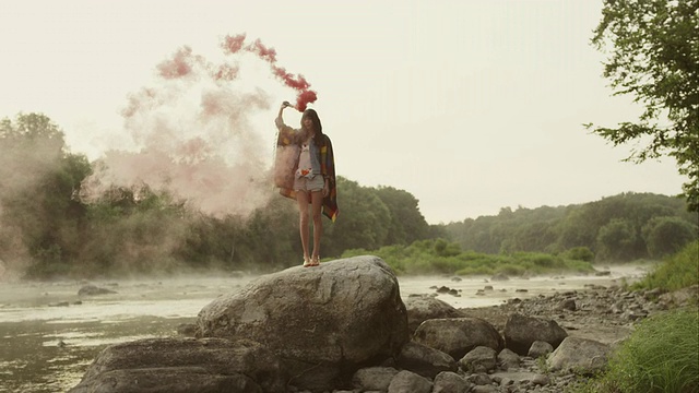 在大自然的大岩石上的女人，周围是红色的烟雾视频素材