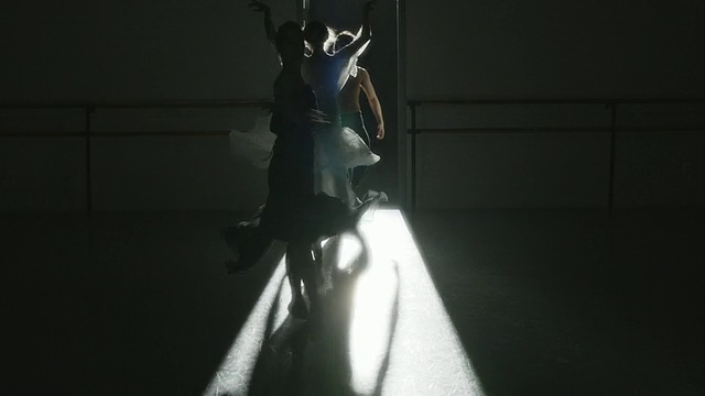 背光拍摄三名芭蕾舞者对着镜头表演脚尖旋转视频下载