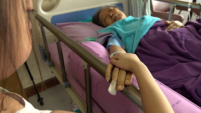 病床上的小女孩牵着一位老年妇女的手视频下载