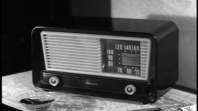 B/W 20世纪50年代近距离男子的手旋转旋钮上小Philco收音机在桌子上视频下载