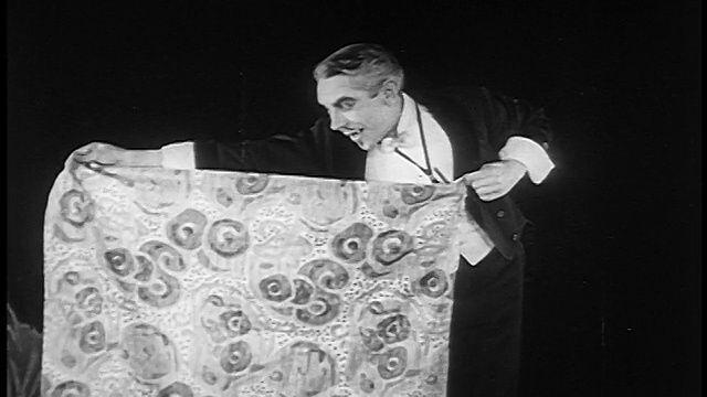 1922年，魔术师(Ernie Adams)在凳子上拿布盖住兔子，移开布露出小鸡视频下载