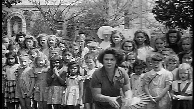 1955年，一名妇女在室外向镜头投掷刀子，背景是一群年轻女孩视频下载