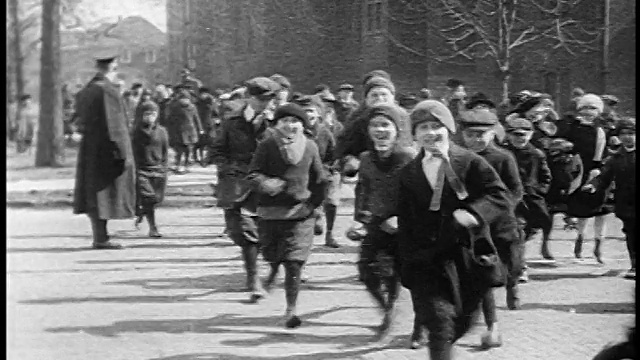 1920年，当汽车经过街道时，交警挥手示意一群奔跑的孩子穿过街道视频下载