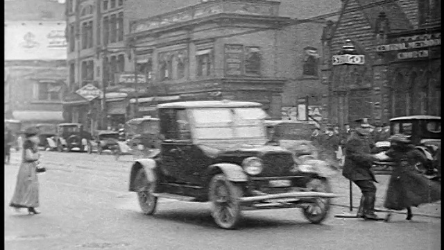 1920年，在城市街道上，交警从迎面而来的汽车的路径上抓过一名过马路的妇女视频下载