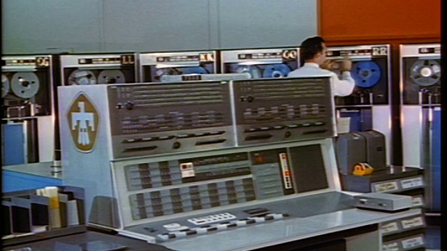 20世纪60年代，一名男子按下磁带驱动器上的按钮，走到电脑室的控制面板上视频素材