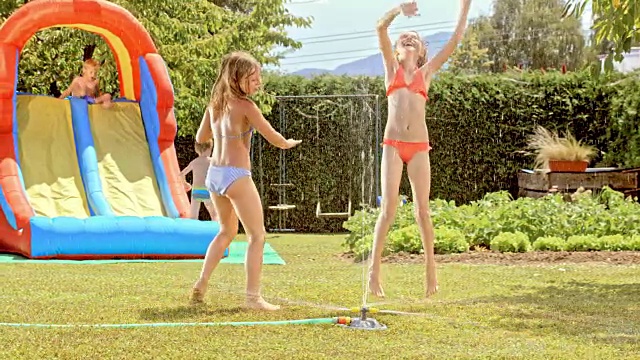 两个小女孩围着洒水器跳舞视频素材