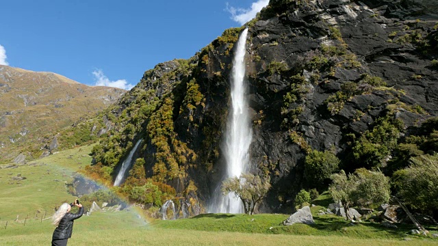 白人妇女拍摄彩虹附近的山瀑布视频素材
