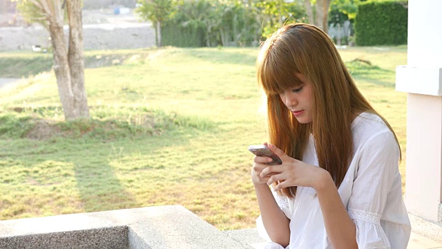 年轻美丽的女孩发智能手机短信视频素材