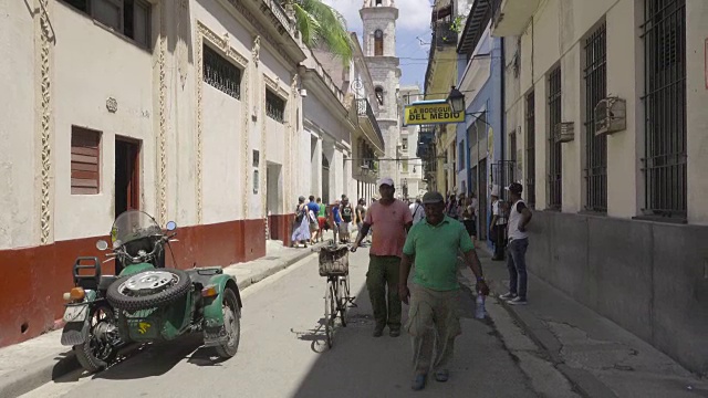 古巴哈瓦那博德吉塔恩米迪奥大街。游客在散步，前景是一辆有边车的旧摩托车。视频下载