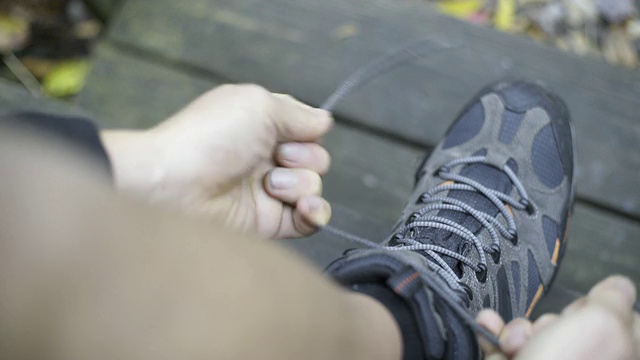 一位老人在离开小屋去远足之前系好他的登山靴。视频下载