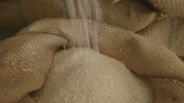 一勺大米被缓慢地倒入袋子里/印度新德里视频下载