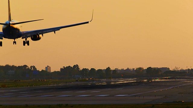 飞机在夕阳下降落在巴塞罗那机场，用长焦镜头拍摄冒烟的车轮。视频素材