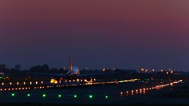 一架飞机在夜间降落在巴塞罗那机场，用长焦镜头拍摄了冒烟的轮子。视频素材