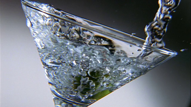 慢镜头拉近清晰的液体被倒入马提尼杯与橄榄视频素材