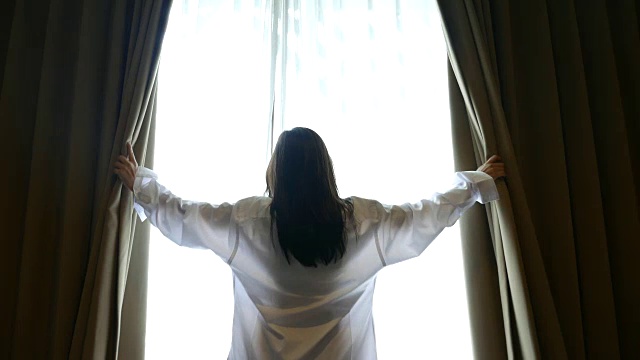 年轻女子在窗前举起双手，生活方式的概念视频素材
