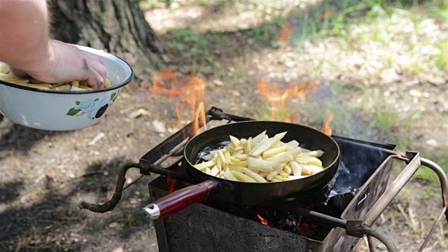 男人在篝火上准备炸土豆。视频素材
