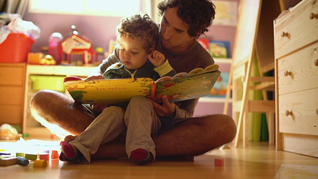 一位父亲给他的小儿子读故事。视频素材