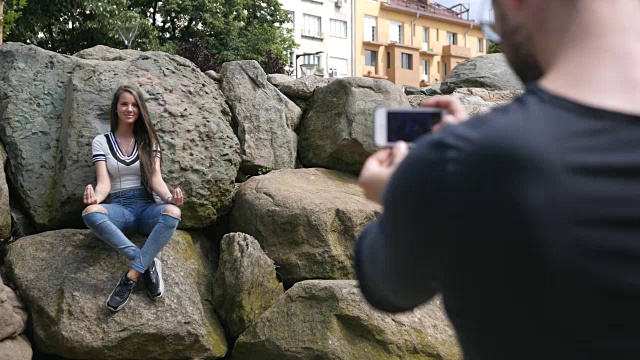 一名年轻男子用智能手机给女友拍照视频下载