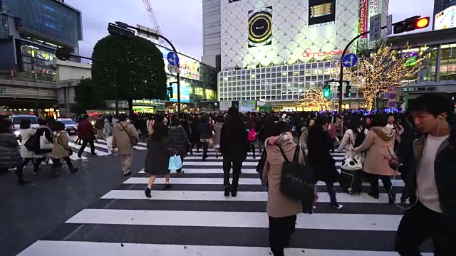 周日傍晚，镜头正穿过涩谷十字路口前往涩谷站。并拍摄行人，城市景观和涉谷站在十字路口。视频素材