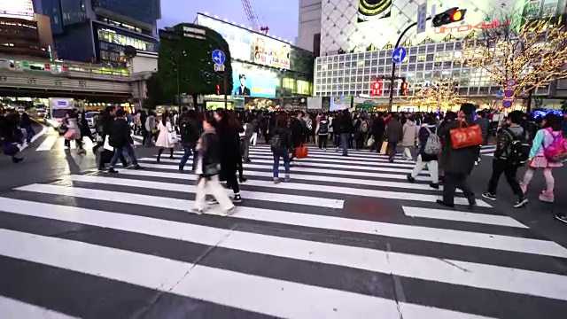 周日傍晚，镜头正穿过涩谷十字路口前往涩谷站。并拍摄行人，城市景观和涉谷站在十字路口。视频素材