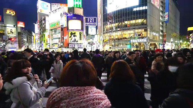 周日傍晚，镜头正穿过涩谷十字路口前往涩谷中心。拍摄城市夜景和十字路口的行人。视频素材