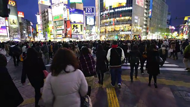 周日傍晚，镜头正穿过涩谷十字路口前往涩谷中心。旋转的摄像头捕捉到夜晚的城市景观和行人在十字路口。视频素材