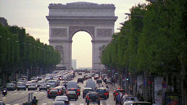 高角度起重机拍摄了香榭丽舍大街上的车流，两旁是树木，人们穿过街道+凯旋门/巴黎视频素材