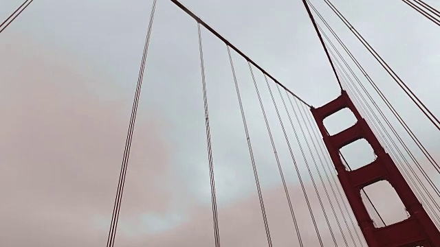 低角度跟踪拍摄移动通过支持电缆和塔金门大桥。视频素材