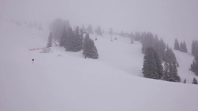 有雾，山上的雪景上正在下雪。人们在底部滑雪和滑雪缆车。视频下载