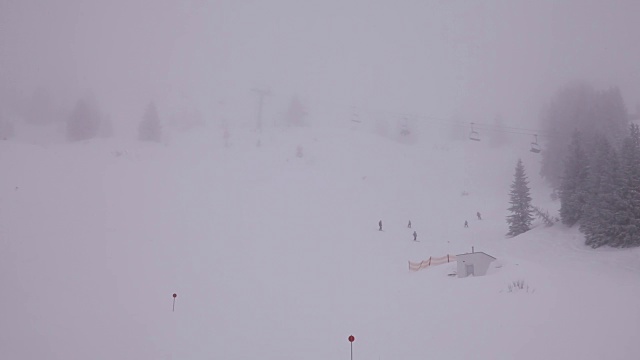 这是山中一个雾蒙蒙的时刻。有些人在滑雪，滑雪名单在移动。视频下载