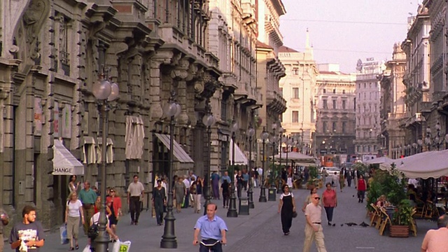 意大利米兰，街道上的行人和骑自行车的人，背景是电车视频下载