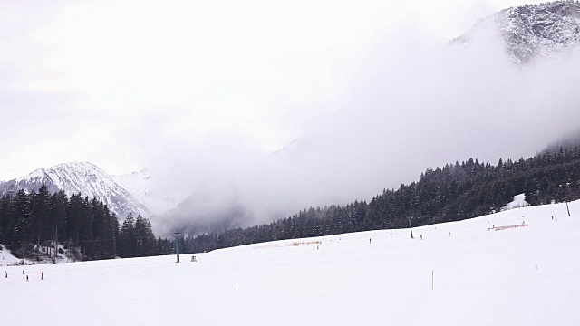 飘落的云在雪景。人们在底部滑雪和滑雪缆车。视频下载