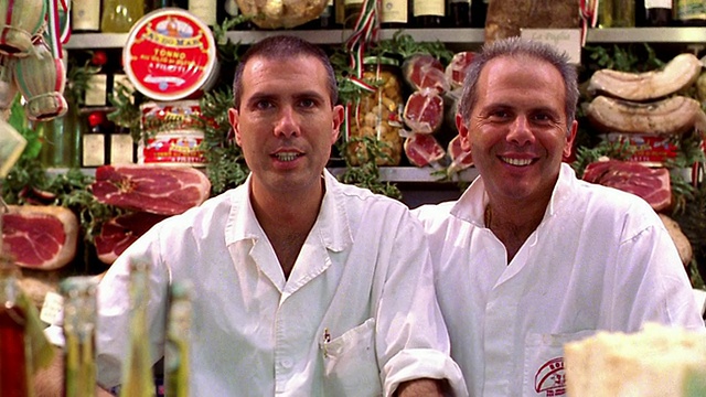 图为两名微笑的男子站在摆满肉类的熟食柜台后面/意大利佛罗伦萨视频素材