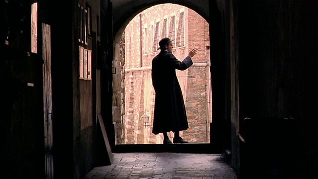 摄影车拍摄了牧师的剪影，他在拱形的走廊中离开摄像机/停下来挥手祝福/佛罗伦萨视频下载