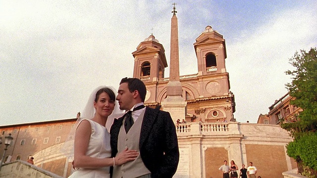 低角度肖像新娘和新郎站在意大利罗马三一教堂前交换亲吻视频下载