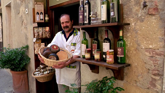 摄影车拍摄肖像的意大利男子拿着篮子满奶酪在商店门口/皮恩扎，意大利视频素材