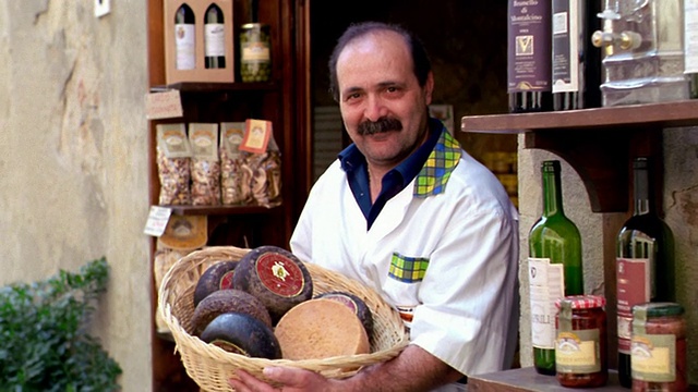 意大利皮恩扎商店门口，一名意大利男子拿着装满奶酪的篮子，近景摄影向他拍摄肖像视频素材