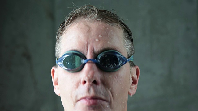 成熟的男性游泳运动员抬起头对着镜头，摘下护目镜视频下载
