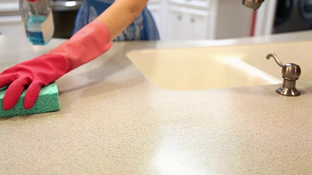 一个妇女正在用海绵和清洁剂清洁厨房。视频素材