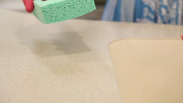一个妇女正在用海绵和清洁剂清洁厨房。视频素材