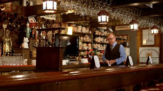 潘成熟的酒保把餐巾纸放在吧台上的空餐厅装饰成传统的英国乡村酒吧的风格视频下载