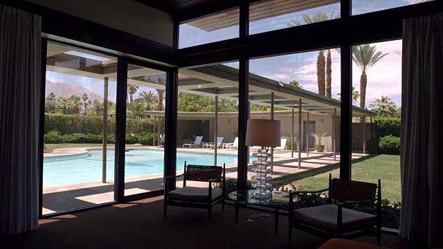 卧室窗户的剪影，面向游泳池和游泳池，位于加利福尼亚沙漠的中世纪现代住宅视频下载