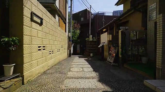 在东京神乐坂，行走的摄像机穿过狭窄的石头楼梯小巷，这条小巷被高墙包围。巷子的角落里有一家前田Ryotei餐厅，巷子的两边还有一些其他的餐厅和酒吧。视频素材