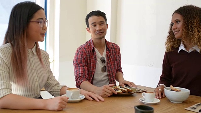 三个年轻的商人在咖啡馆里讨论视频下载