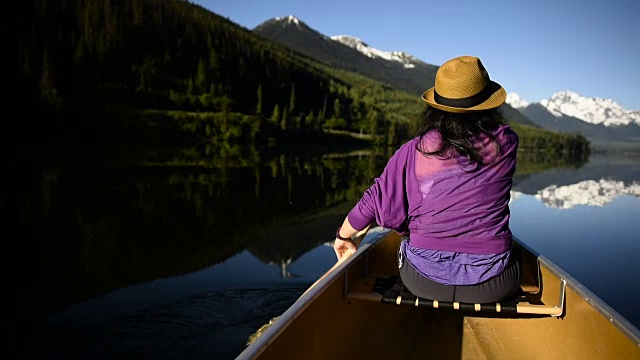 在一个原始的山湖上划独木舟的女人视频素材