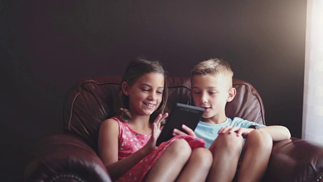 女孩和男孩在平板电脑上玩游戏视频素材